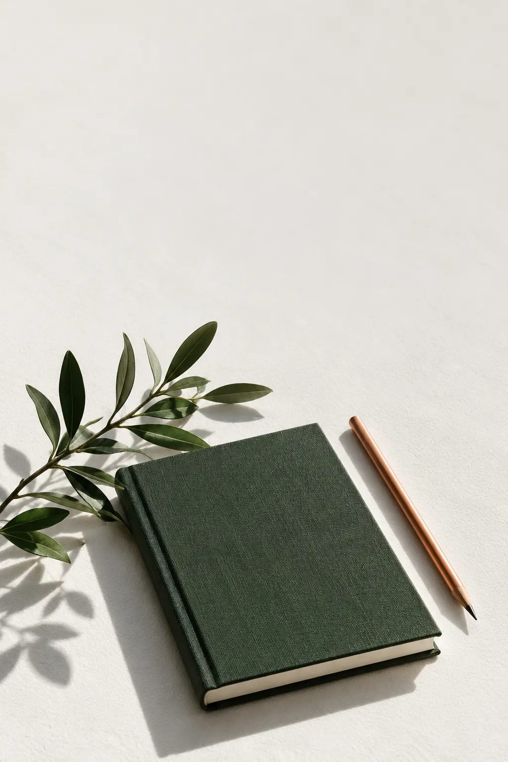 Cuaderno verde y lápiz de cobre con una rama